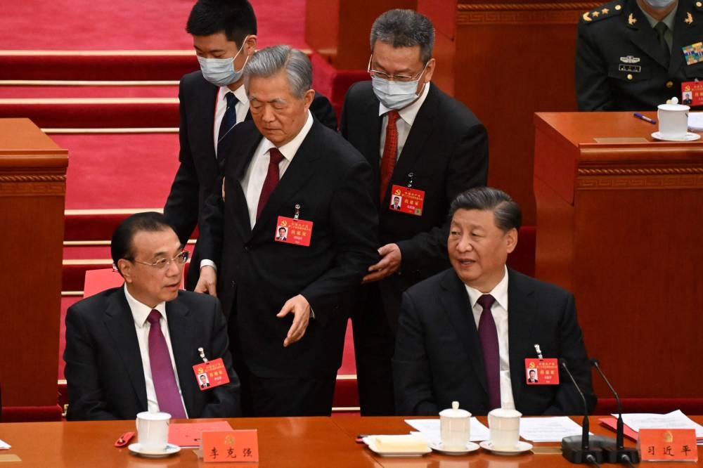 胡锦涛（中）被搀扶着走过习近平身边时，胡向习近平（前右）和中国国务院总理李克强（前左）等人点头示意，接着便离开会场。-法新社-