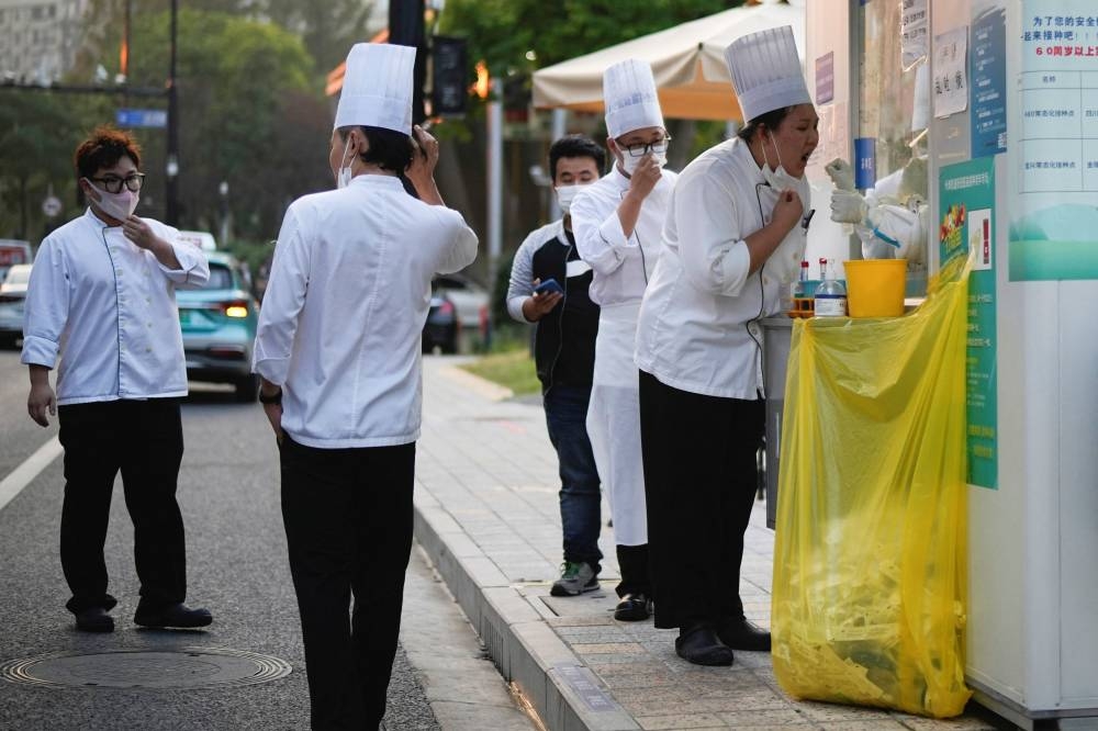 最新一轮新冠疫情正在中国快速蔓延升级。图示上海一间酒店的厨师排队做新冠核酸检测。-路透社-