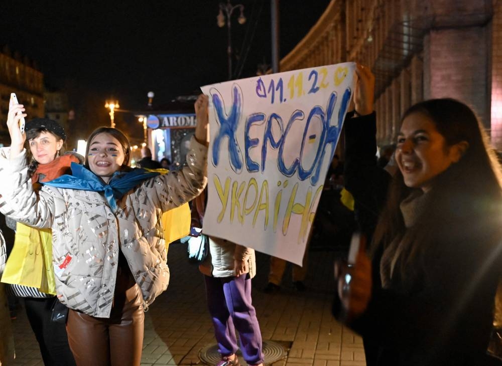 赫尔松居民身披旗帜、开香槟、高唱乌克兰国歌，聚集在基辅的独立广场庆祝获得解放。有人高举写着“2022年11月11日-赫尔松-乌克兰”的纸卡纪念这一天。-法新社-