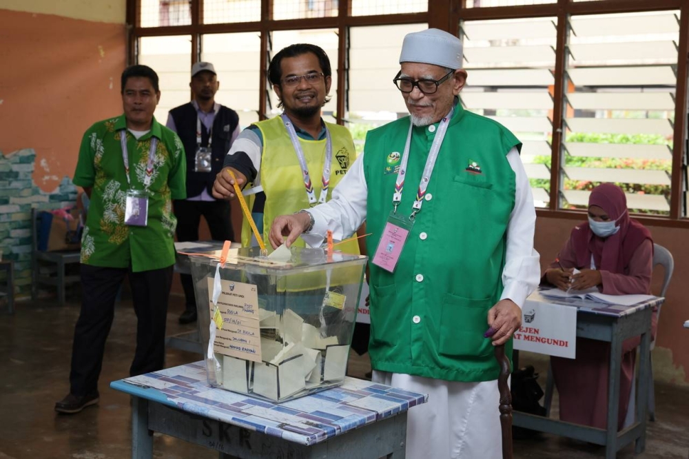 哈迪阿旺（右）穿着印有伊党党徽的背心进入投票中心投票。-马新社-