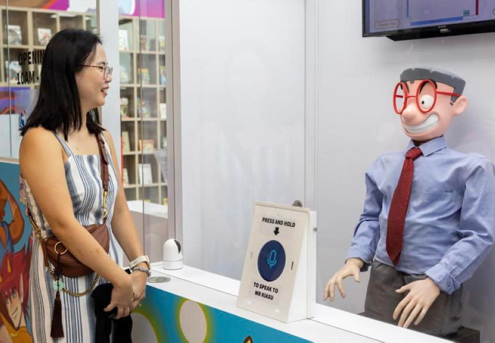“怕输先生机器人”（左）能为公众介绍书籍，以及指导公众如何使用智能闸门。-摘自新加坡国家图书馆管理局的脸书-