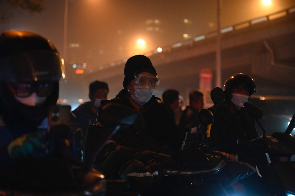 北京周一晚突现沙尘暴，夜色下，北京市区变得模糊一片。除了口罩，有民众还戴上护目镜。-路透社-