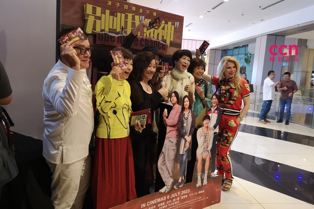 影迷兴奋在《别叫我“赌神”》电影牌板前拍照打卡。