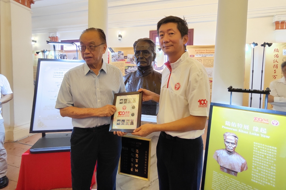 颜登逸（右）颁发百年隆雪华堂纪念邮票给方贵伦留念。-刘家仪摄-