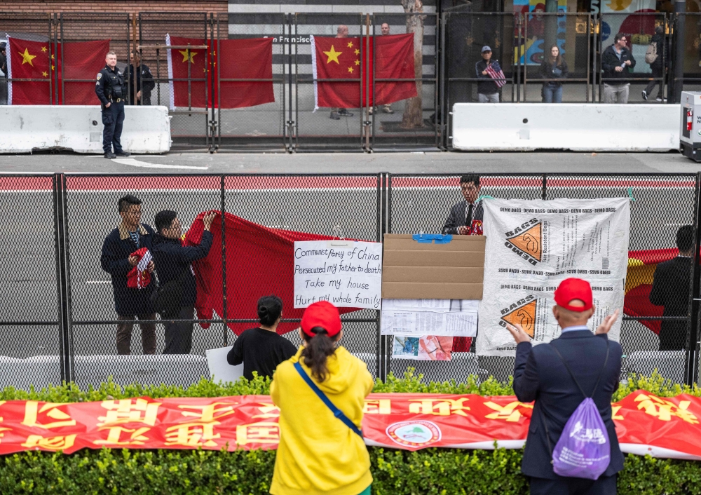示威者在习近平下榻酒店外的栅栏挂上抗议横幅和海报，中国官员忙用红布遮盖。-法新社-