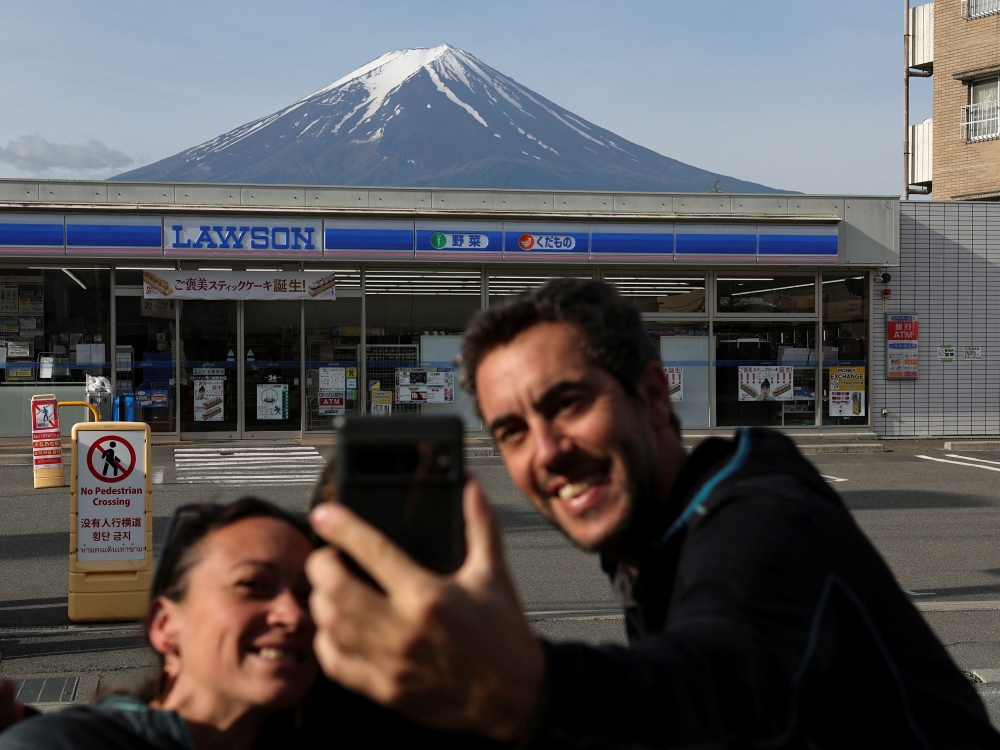 日本连锁便利商店Lawson河口湖站前店因为与店铺后方远处的富士山形成强烈对比,吸引许多外国观光客到此一游。-路透社-