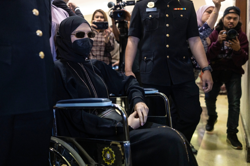 行动不便的莎瓦妮坐着轮椅出庭面控。-Yusof Isa摄-