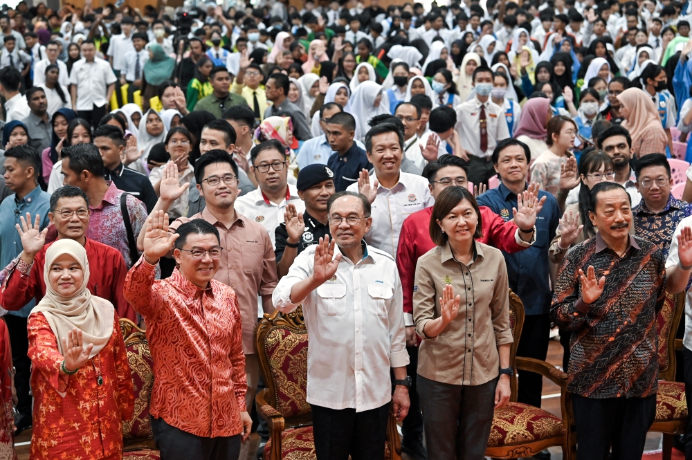 首相安华（中）周六在怡保育才华中举行的打扪国会选区昌明大马关爱捐赠仪式上，与出席嘉宾以及学生合影。-马新社-
