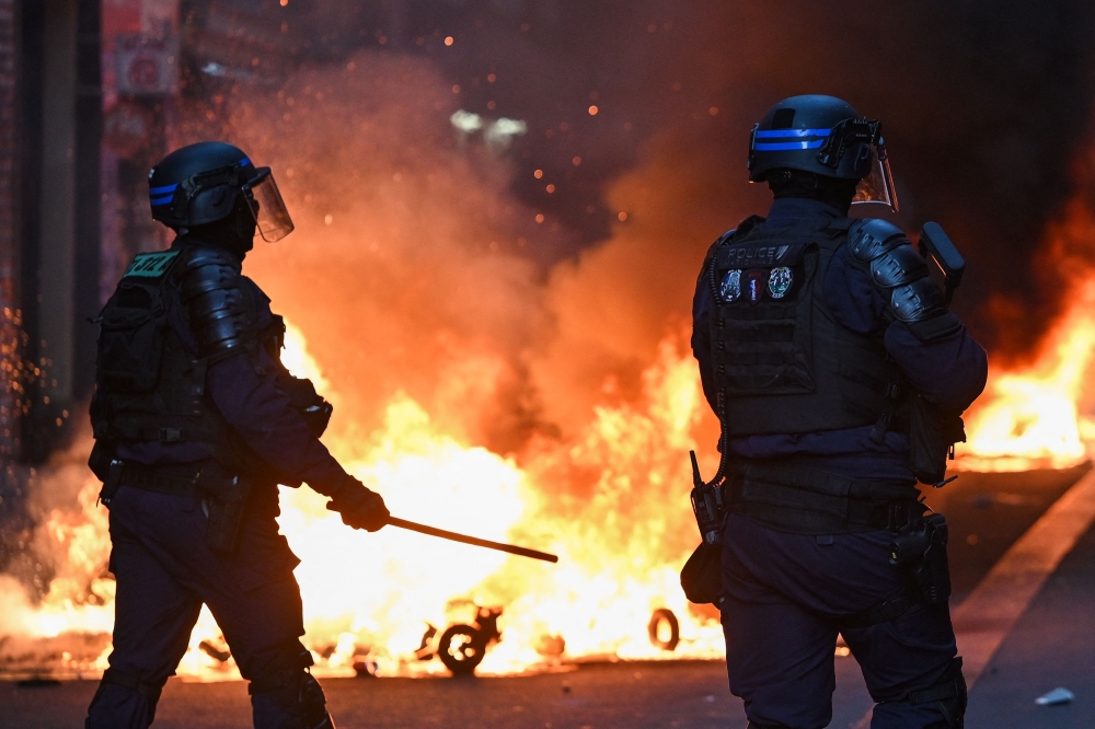巴黎共和国广场上周六爆发冲突，保安部队站在圣殿郊区街的一处火堆前。-法新社-