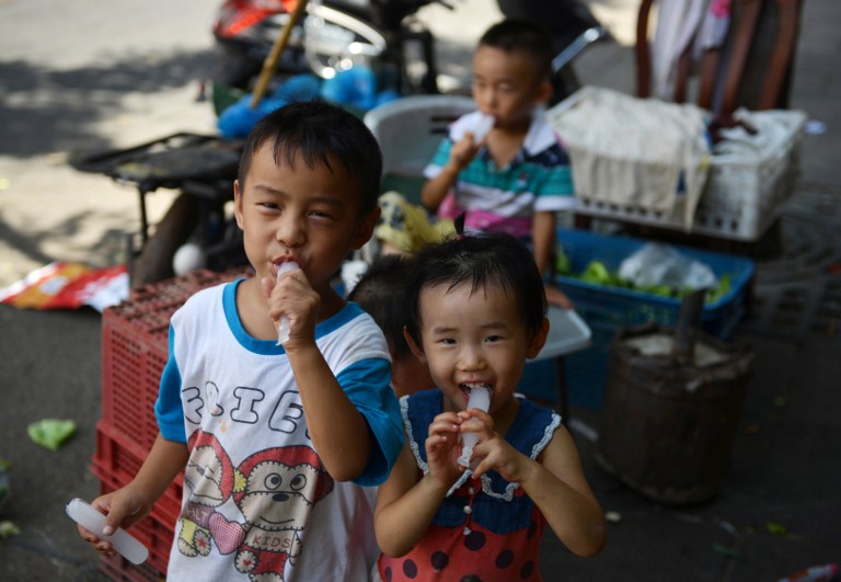 Children suck on ice lollies to keep cool on a street in Shanghai on August 15, 2013. The Chinese government said today it will ease its one-child policy. u00e2u20acu201d AFP pic