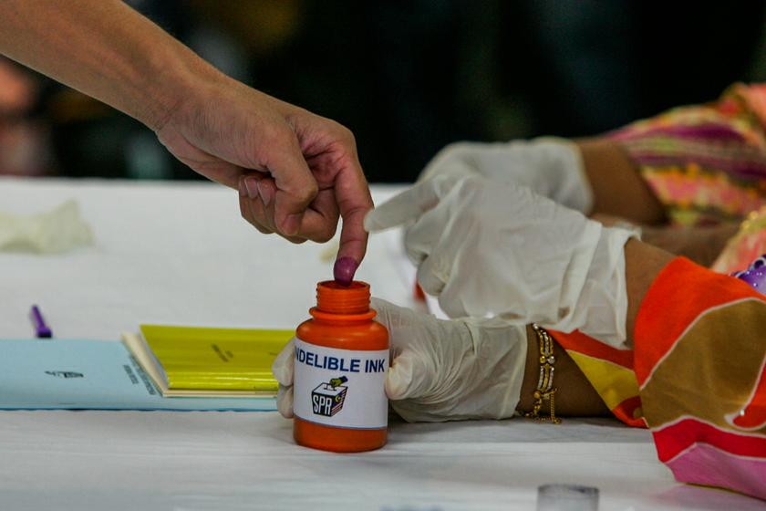 The Election Commission officer demonstrating how voters should dip their index finger into the indelible ink during the Kuala Besut by-election at Besut District Office operations room. u00e2u20acu201c Picture by Saw Siow Feng