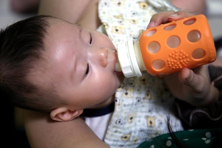 A baby drinks milk from a bottle. u00e2u20acu201c Picture by Saw Siow Feng