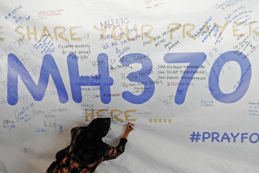 A woman writes a message of support and hope for the passengers of the missing Malaysia Airlines MH370 on a banner at Kuala Lumpur International Airport March 12, 2014. u00e2u20acu201d Reuters pic