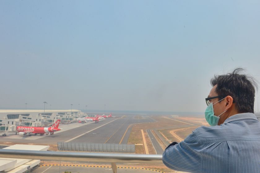 A man wears a facial mark to protect himself from the haze as he looks at some planes near the KLIA2 runway in Sepang, on June 24, 2014. u00e2u20acu201d Picture by Saw Siow Feng
