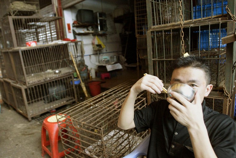 File picture shows a stall owner in the South China Wild Animal Market in Guangzhou eating his breakfast next to empty cages which used to house raccoon dogs, civet cats and snakes for sale as food. u00e2u20acu201d AFP pic