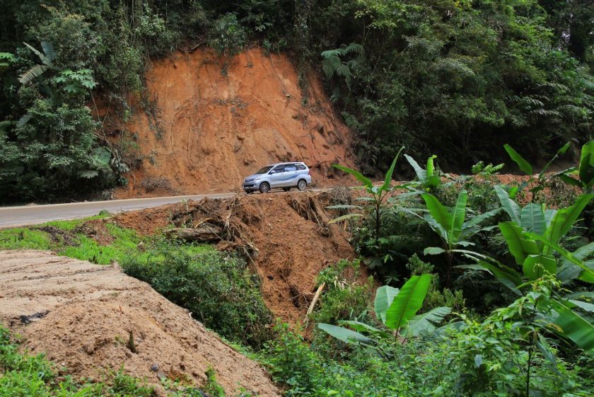 A car drives past a section of the road where a small landslide occurred earlier. u00e2u20acu201d Picture by Saw Siow Feng