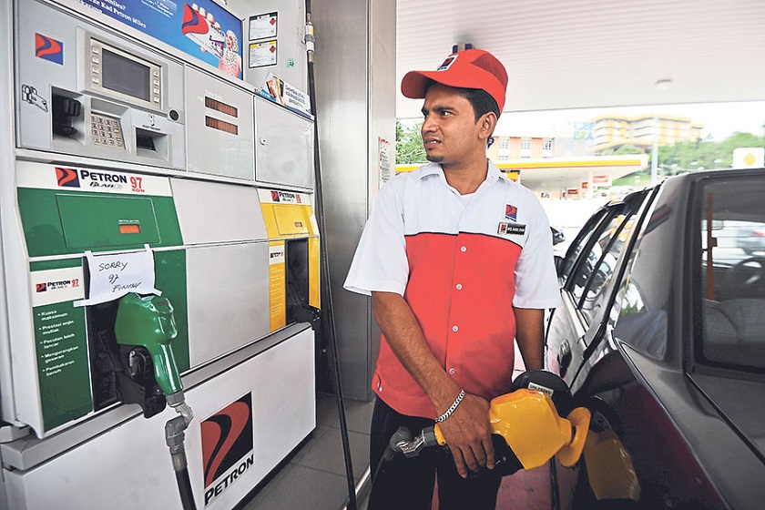 Pump attendant Muhd Babul Khan, 26, who works at a petrol station in Petaling Jaya, fills a car with RON95 but a sign at the green pump says it has run out of RON97.  u00e2u20acu201d Picture by Azinuddin Ghazali