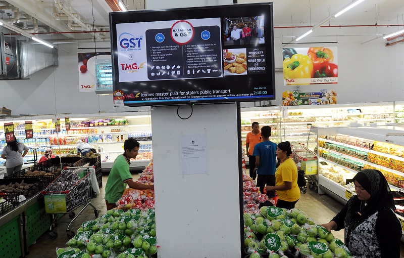 A display board depicting general information on the implementation of the GST is seen as people shop at a supermarket in Kuantan, March 31, 2015. u00e2u20acu201d Bernama pic