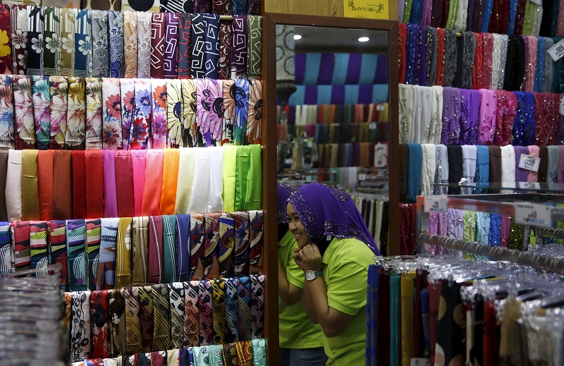 A sales assistant tries on a headscarf at the Ramadan bazaar ahead of the Hari Raya Aidilfitri celebrations in Kuala Lumpur, July 14, 2015. u00e2u20acu201d Reuters pic
