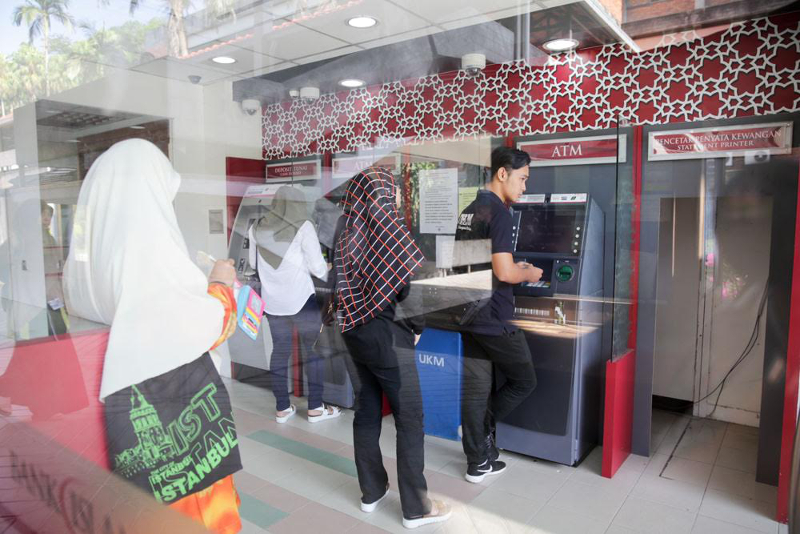 Sekumpulan pelajar pengajian tinggi di Bangi mengeluarkan wang di mesin ATM. PTPTN sedang mengkaji memotong peminjam yang bekerja dalam sektor swasta. u00e2u20acu2022 Foto oleh Choo Choy May