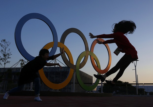 Chinese journalists jump in front of the rings at sunset in the Olympic Park July 31, 2016. u00e2u20acu201d Reuters pic