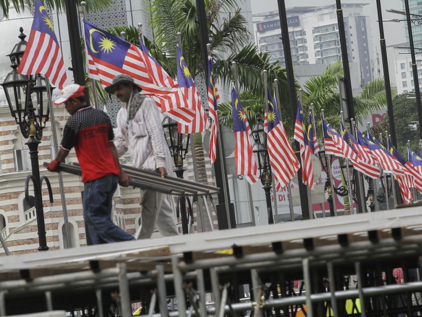 Workers walk past the Jalur Gemilang in downtown Kuala Lumpur August 11, 2016. Malaysia celebrates its 59th National Day on August 31. u00e2u20acu2022 Picture by Yusof Mat Isa