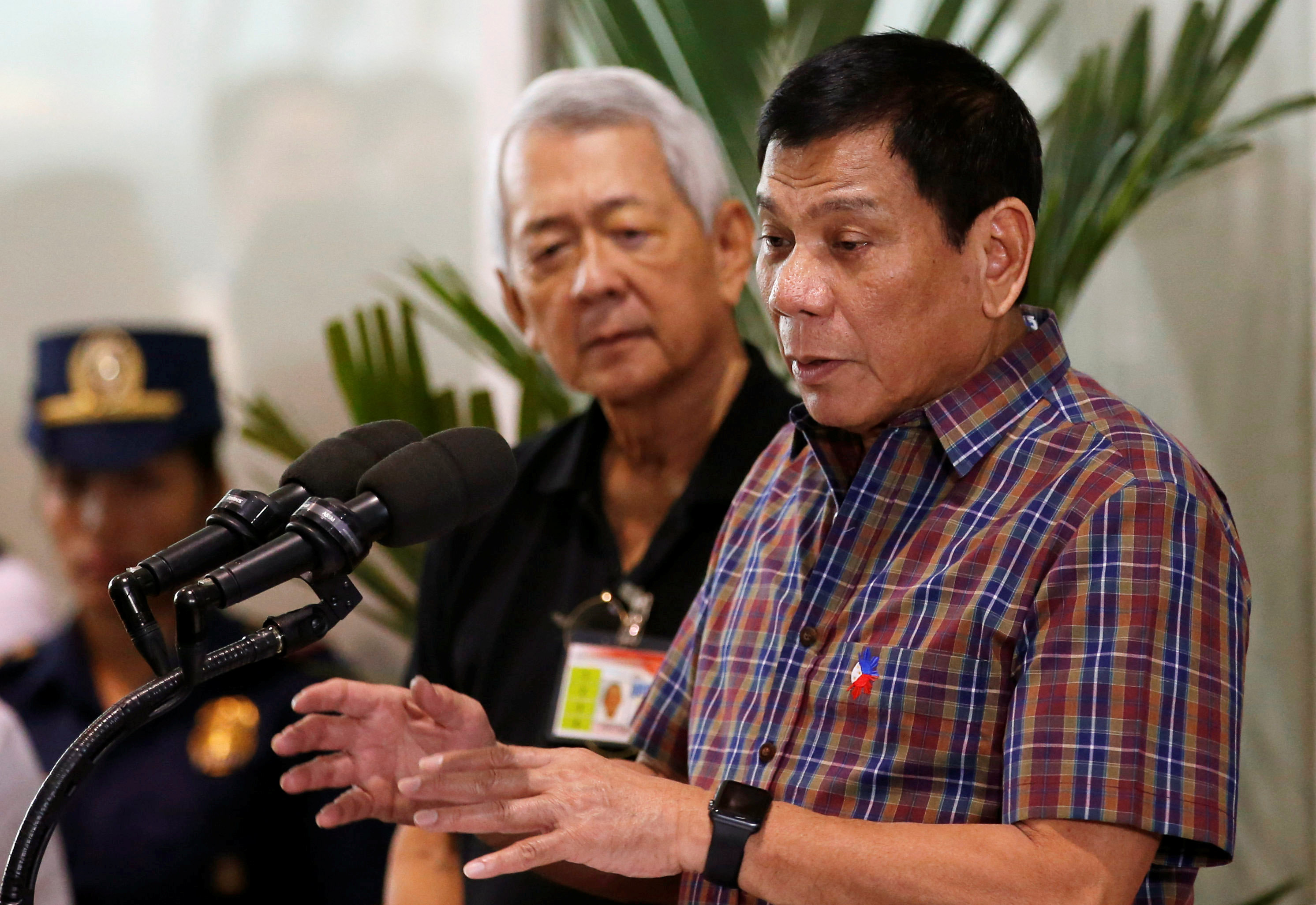 Philippine President Rodrigo Duterte speaks next to Foreign Affairs Secretary Perfecto Yasay, before Filipino workers who were repatriated by the Philippine government from Saudi Arabia, upon their arrival at the Ninoy Aquino International Airport in Mani