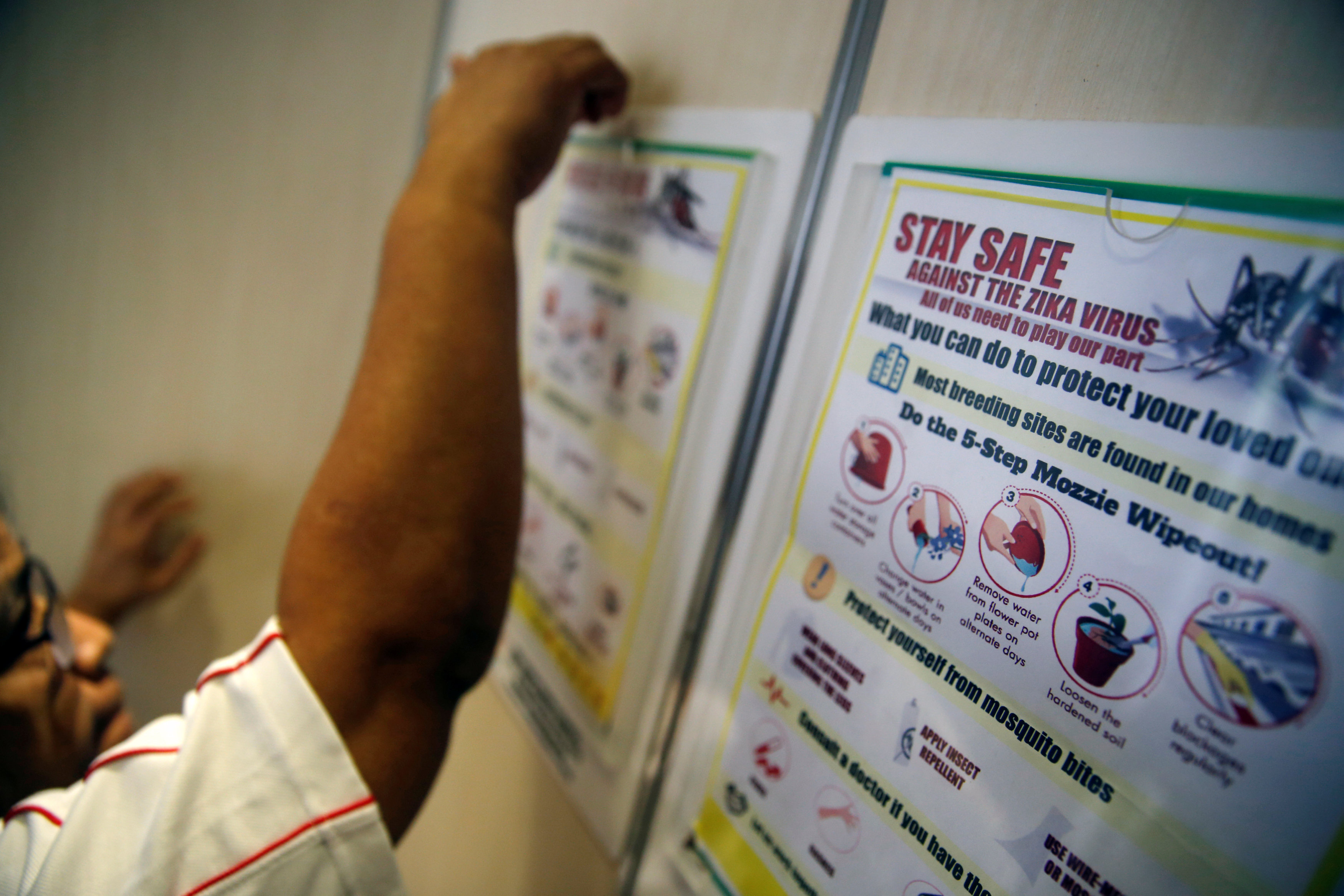 A resident volunteer puts up posters in a lift of a public housing estate in a Zika cluster in Singapore September 2, 2016. REUTERS/Edgar Sun