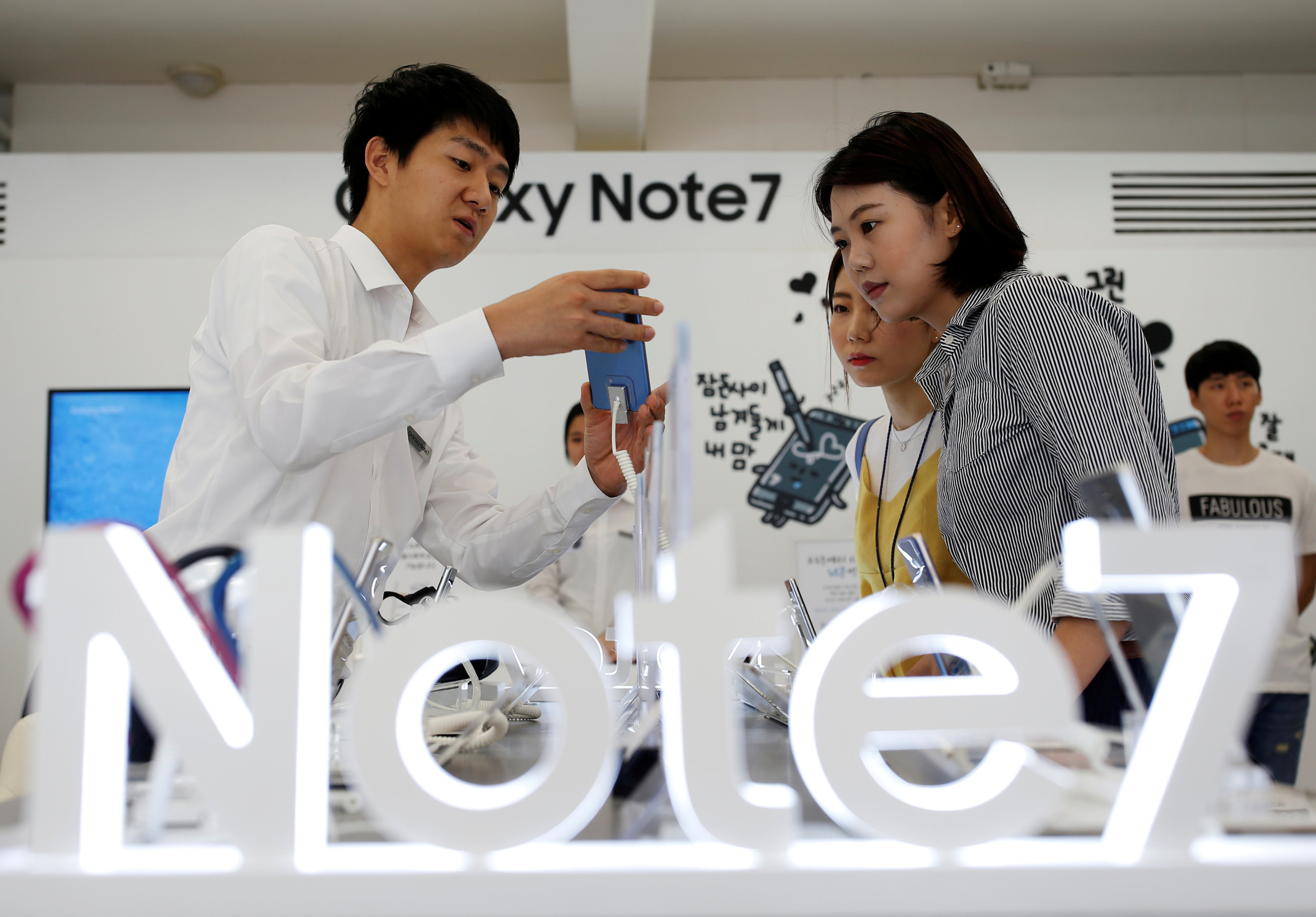An employee helps customers purchase a Samsung Electronics' Galaxy Note 7 new smartphone at its store in Seoul, South Korea, September 2, 2016. REUTERS/Kim Hong-Ji/File Photon