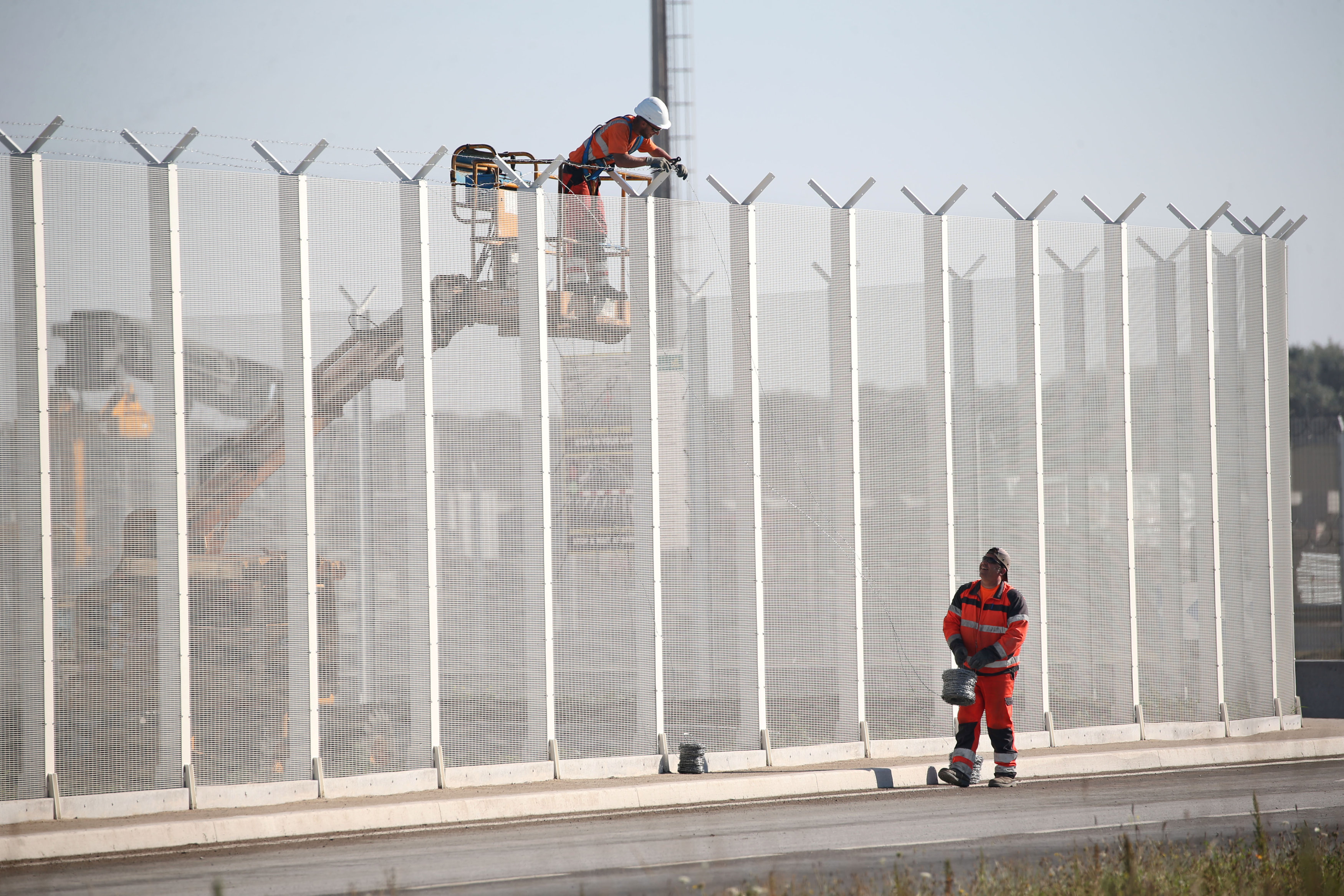Workers set-up barbed wires on top of a fence along the harbour of Calais to prevent migrants jumping aboard lorries, France, September 7, 2016. REUTERS/Charles Platiau