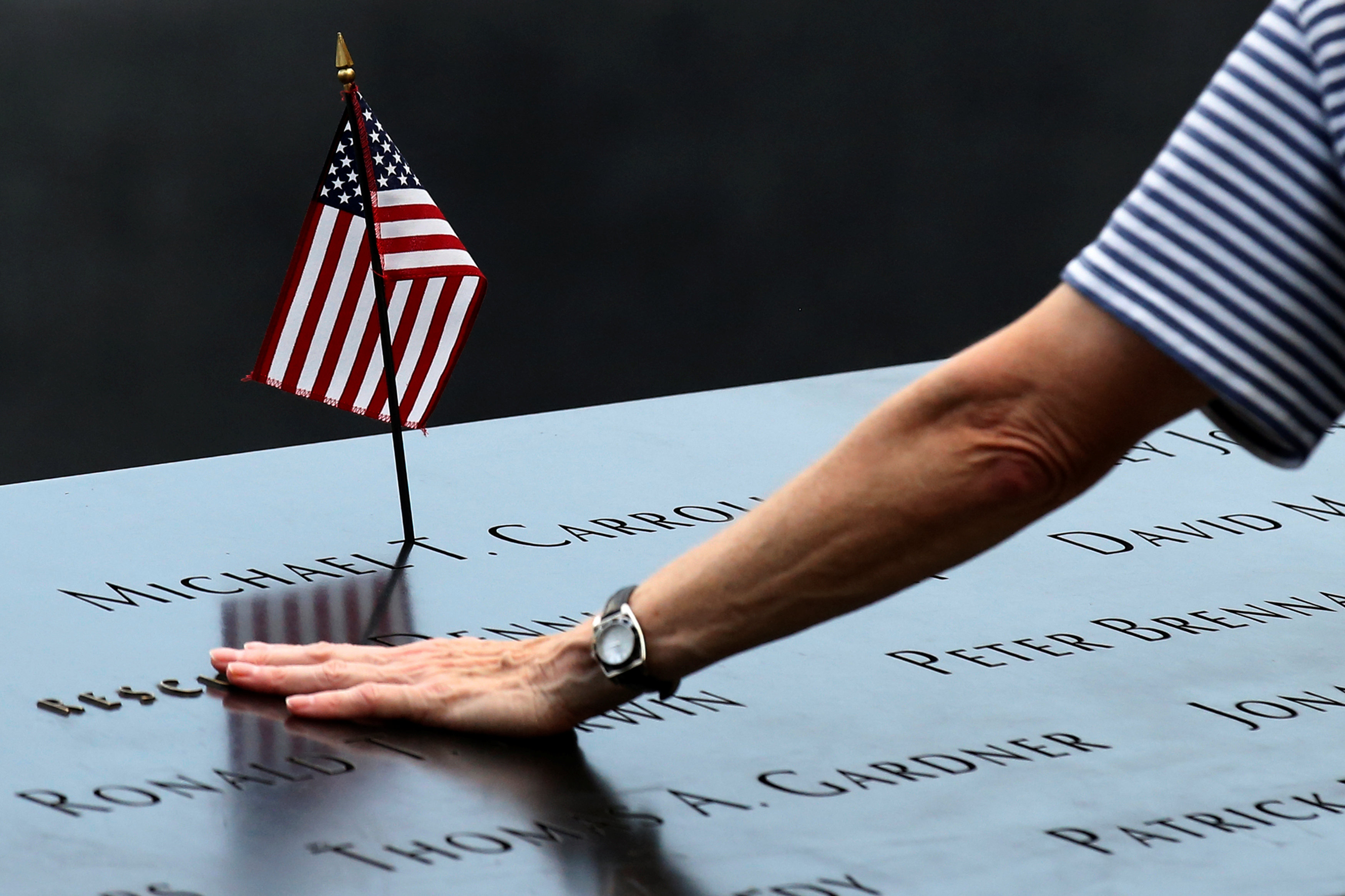A woman places her hand over a name on the memorial at the National September 11 Memorial and Museum in Lower Manhattan in New York City, U.S., September 9, 2016. REUTERS/Brendan McDermidn