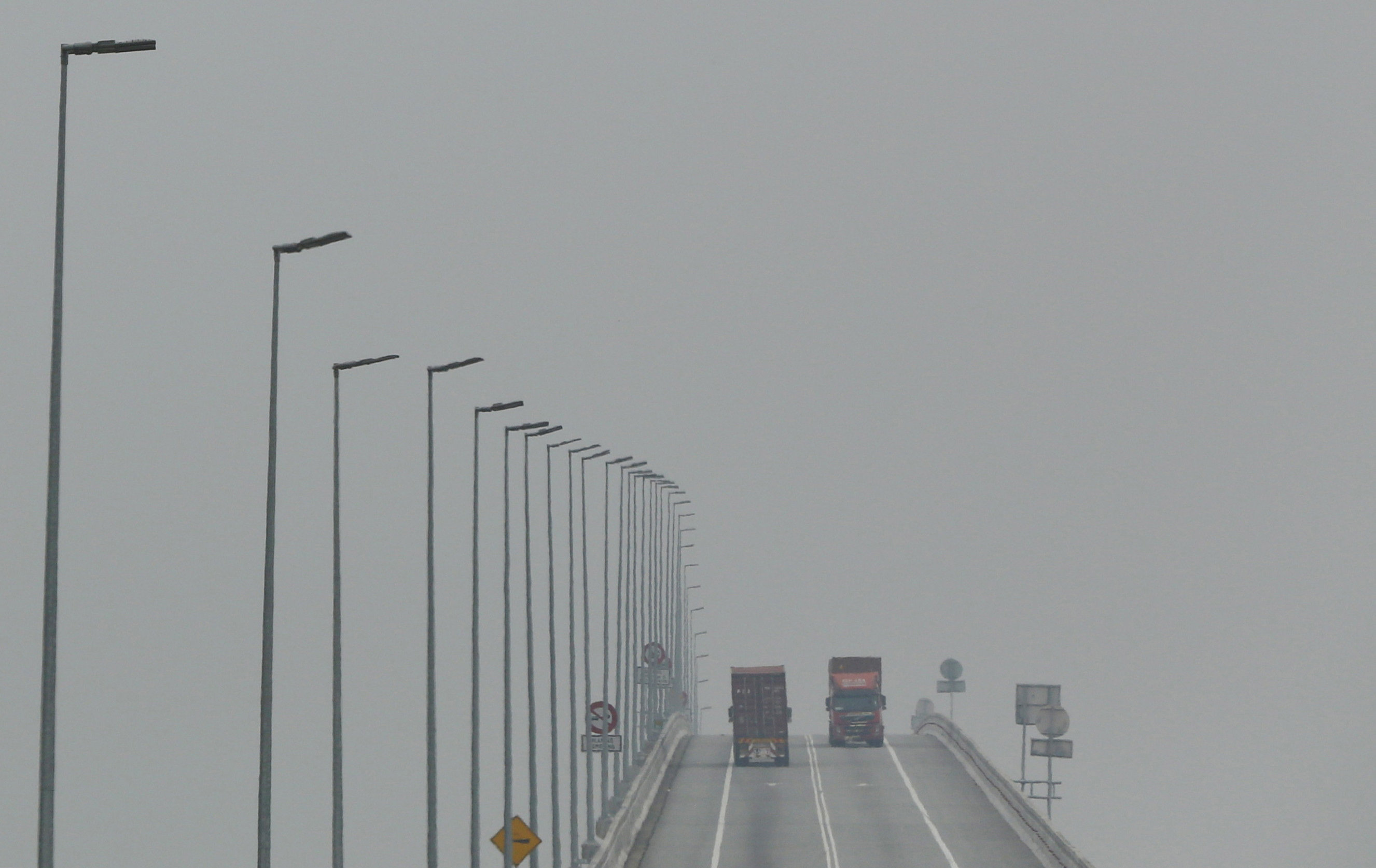 FILE PHOTO - Lorries cross a bridge shrouded in haze in Klang, Malaysia, October 7, 2015. REUTERS/Olivia Harris/File Photon