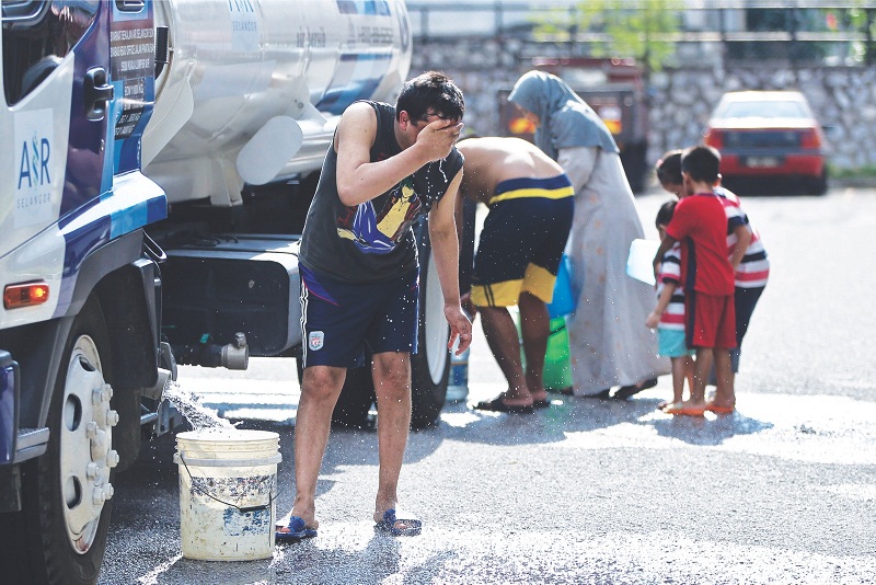 A resident washes his face while filling up water from a Syabas tanker.u00e2u20acu201d Picture by Azneal Ishak