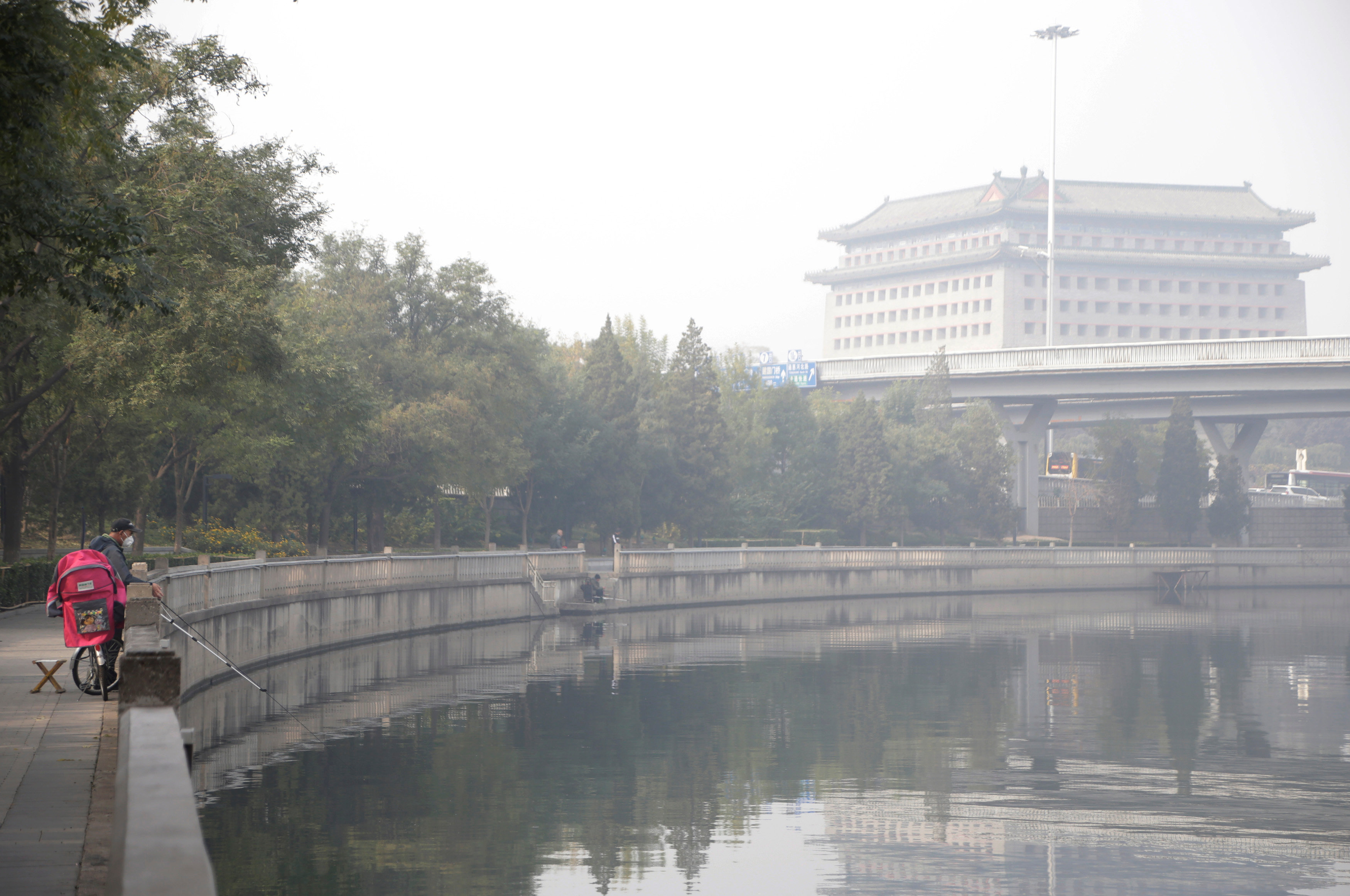 A man wearing a mask fishes near the Dongbianmen Gate (R) on a hazy day in Beijing, China, November 4, 2016. REUTERS/Jason Lee TPX IMAGES OF THE DAYn