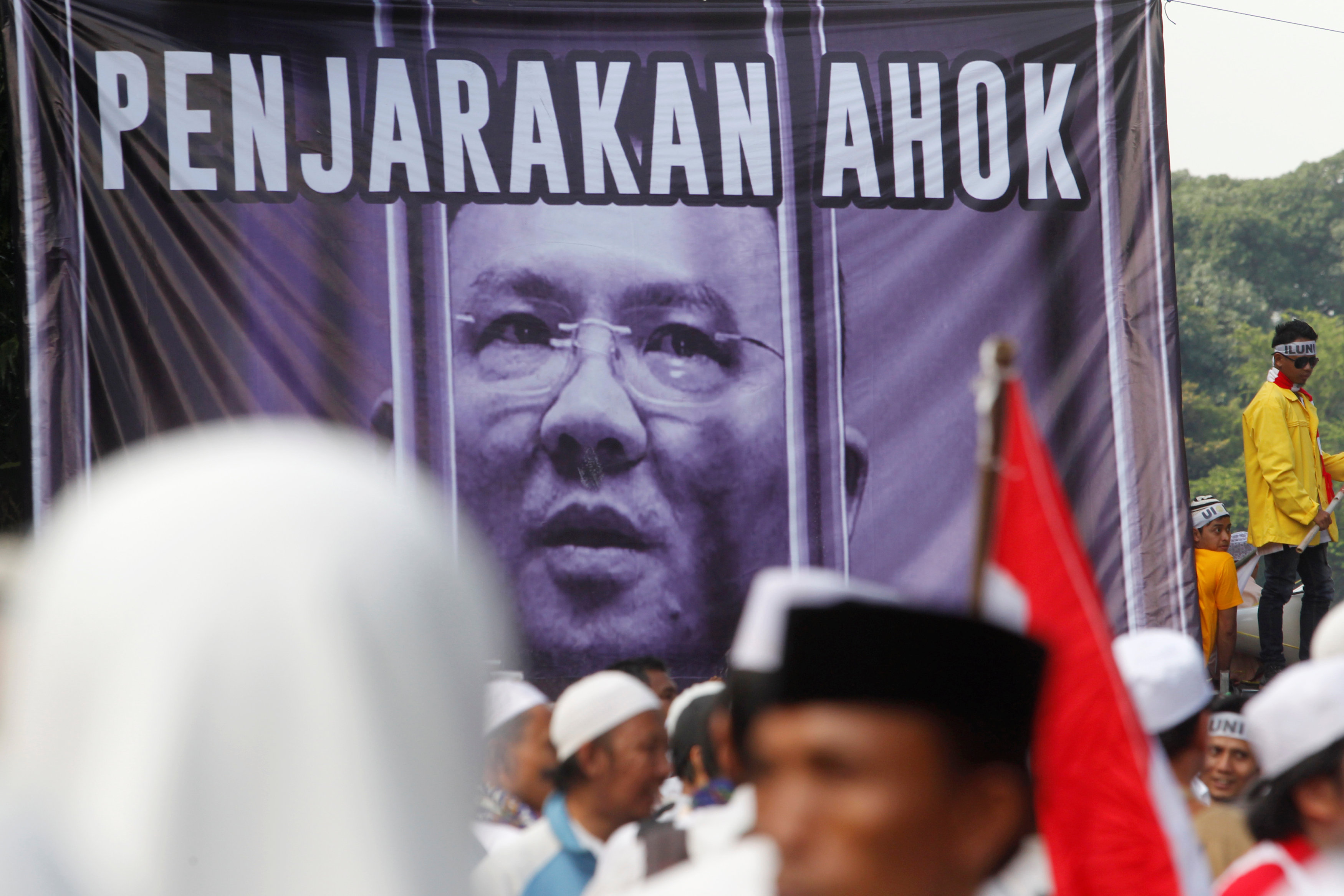 Members of hardline Muslim groups stand around a poster during protest against Jakarta's incumbent governor Basuki Tjahaja Purnama, an ethnic Chinese Christian running in the upcoming election, in Jakarta, Indonesia, November 4, 2016. Poster said ,Ahok sh