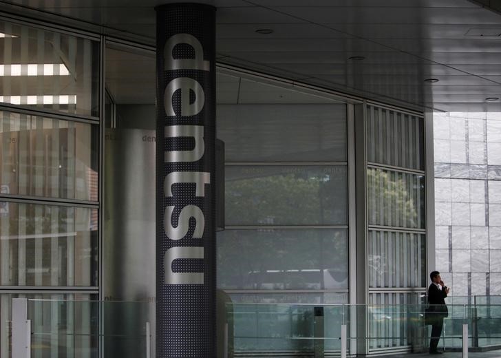 A man speaks on his mobile phone near a logo of Dentsu Co. at the entrance of the company headquarters in Tokyo July 12, 2012. REUTERS/Issei Kato/File photon