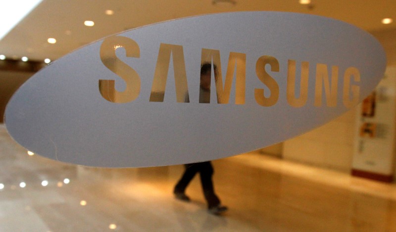 A man walks behind a logo of Samsung Electronics at the company's headquarters in Seoul April 30, 2010. REUTERS/Jo Yong-Hak/File Photon