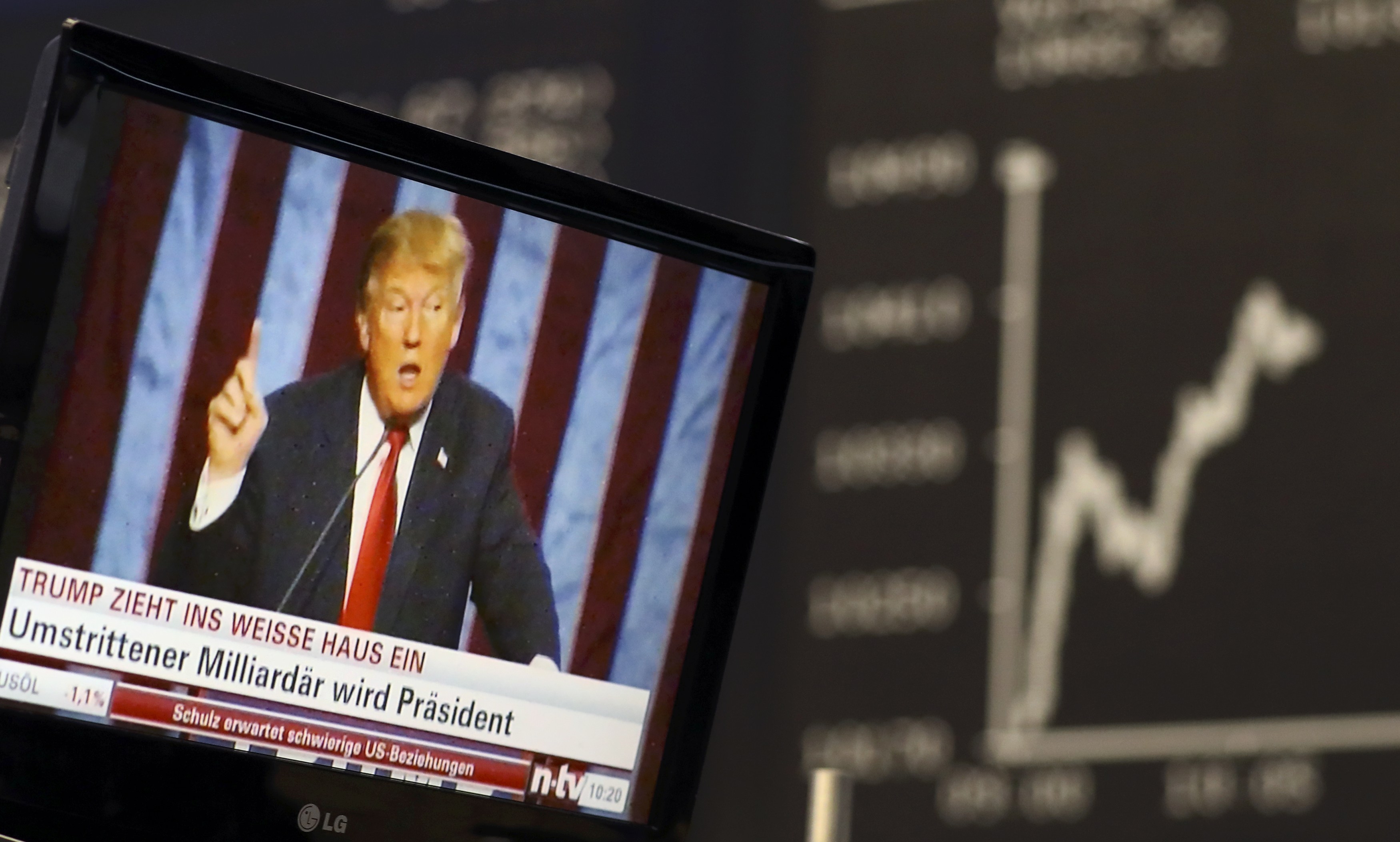 A TV screen showing U.S. President-elect Donald Trump is pictured in front of the German share price index, DAX board, at the stock exchange in Frankfurt, Germany, November 9, 2016. REUTERS/Staff/Remoten