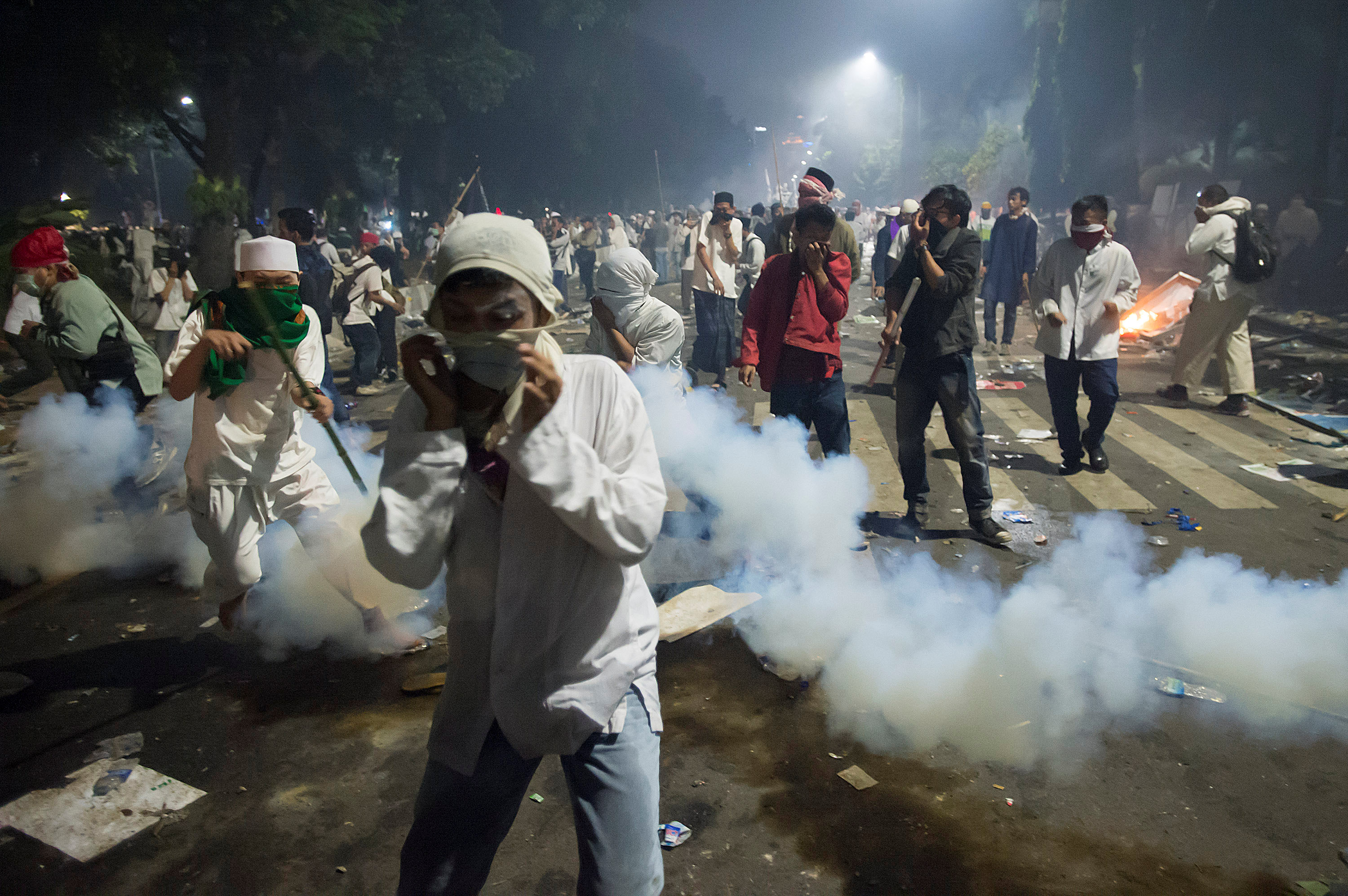 Muslim hardline protesters cover their faces as police fire tear gas during a protest against Jakarta's incumbent governor Basuki (Ahok) Tjahaja Purnama, an ethnic Chinese Christian running in the upcoming election, in Jakarta, Indonesia, November 4, 2016