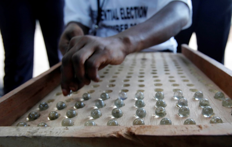 冈比亚选民是用弹珠投票，投票完成后票务人员会将弹珠从票桶倒出，铺在有孔洞的泥板上进行计票。-路透社-