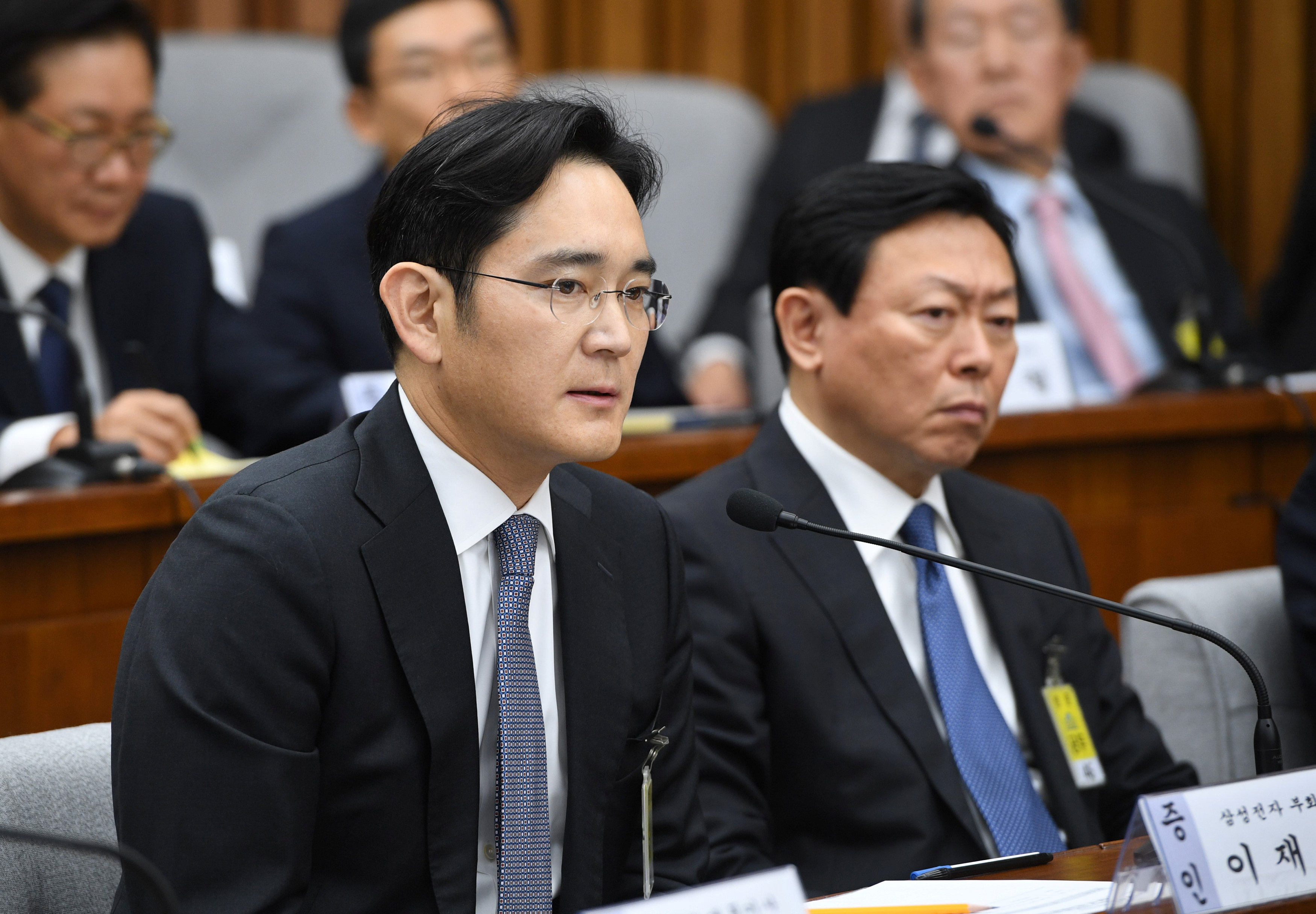 Samsung Group's heir-apparent Lee Jae-yong (L) answers a question as Lotte Group Chairman Shin Dong-Bin (R) listens during a parliamentary probe into a scandal engulfing President Park Geun-Hye at the National Assembly in Seoul on December 6, 2016. The pu
