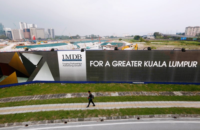 A man walks past a 1 Malaysia Development Berhad (1MDB) billboard at the funds flagship Tun Razak Exchange development in Kuala Lumpur, March 1, 2015. REUTERS/Olivia Harris/File Photon