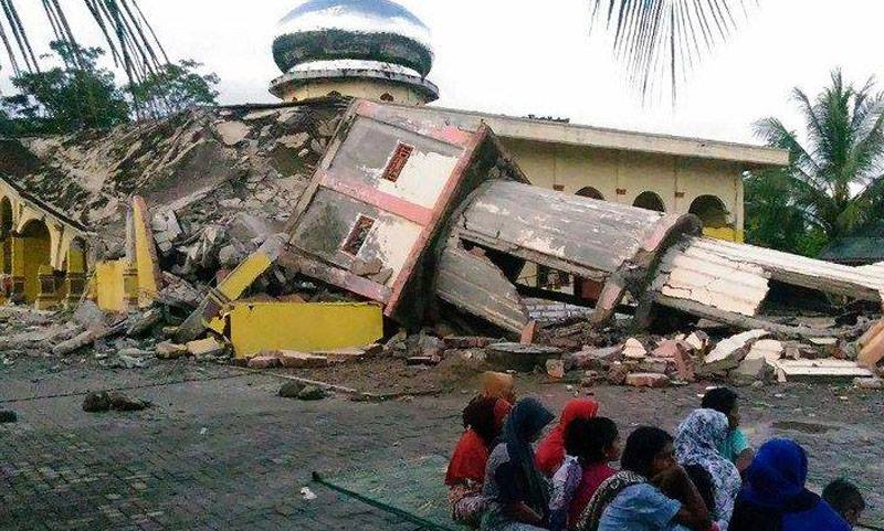 Residents gather outside a damaged mosque, its minaret reduced to rubble following its collapse, after a 6.4-magnitude earthquake struck the town of Pidie, Indonesia's Aceh province in northern Sumatra, on Dec 7, 2016. -AFP-n