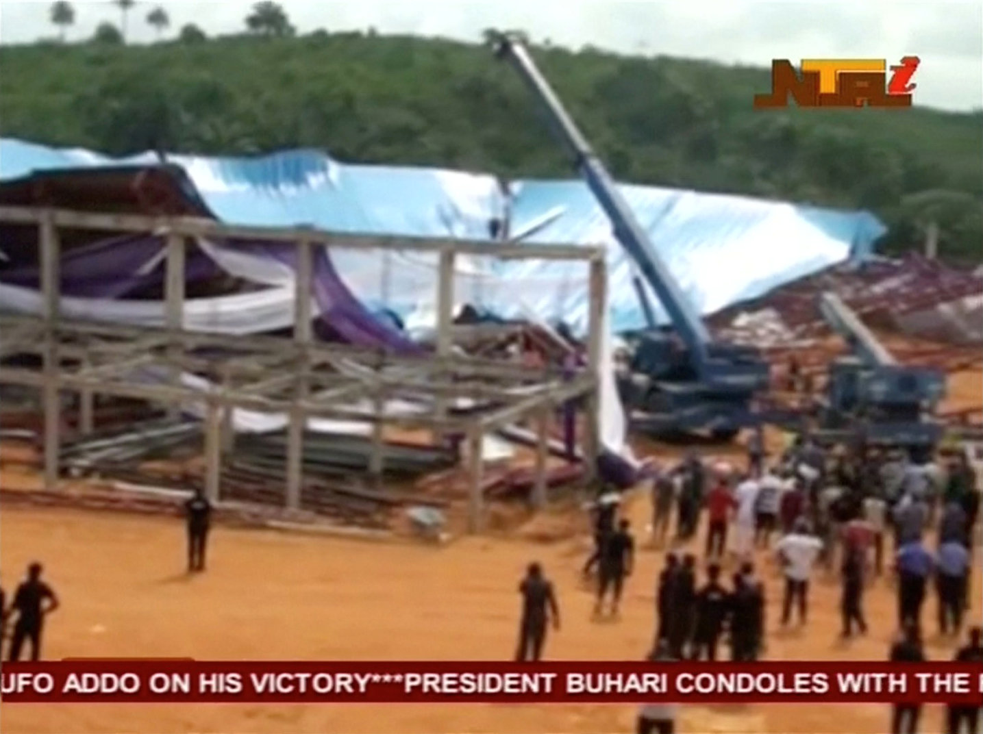 People stand near the remains of a church which collapsed during a service in the southern city of Uyo in Akwa Ibom state, Nigeria in this still image from video December 10, 2016. Video taken December 10, 2016. NTA via REUTERS TV ATTENTION EDITORS - THIS