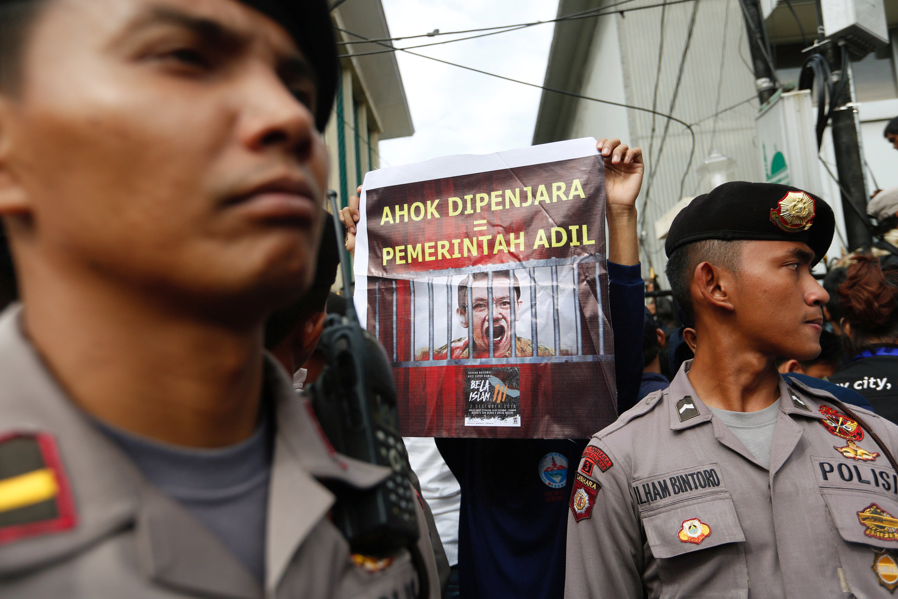 A protester holds a banner outside a court during the first day of the blasphamy trial of Jakarta's Governor Basuki Tjahaja Purnama, also known as Ahok, in Jakarta, Indonesia December 13, 2016. The banner reads, ,Ahok in prison = A fair government,. REUTE