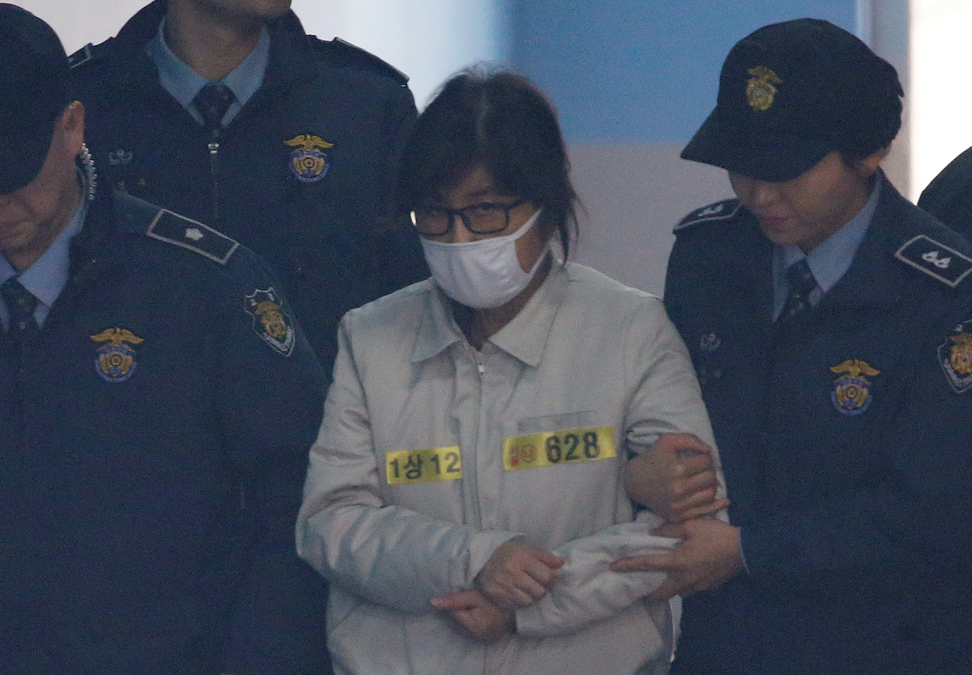 Choi Soon-sil (wearing white mask), a long-time friend of South Korean President Park Geun-hye who is at the center of the South Korean political scandal involving Park, arrives for her first court hearing in Seoul, South Korea, December 19, 2016. REUTERS