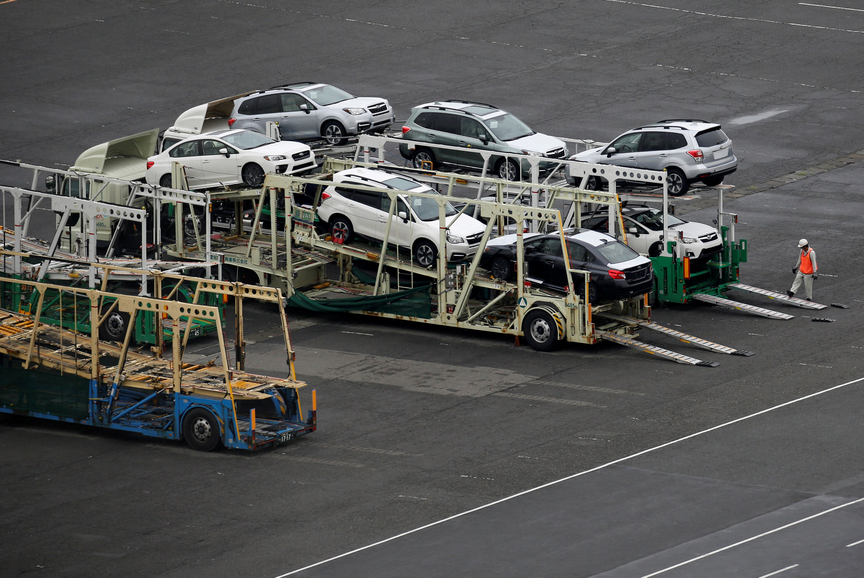 A worker walks beside newly produced cars at Keihin industrial zone in Kawasaki, Japan, September 14, 2016. REUTERS/Toru Hanai/File Photo GLOBAL BUSINESS WEEK AHEAD PACKAGE - SEARCH BUSINESS WEEK AHEAD 19 DEC FOR ALL IMAGESn