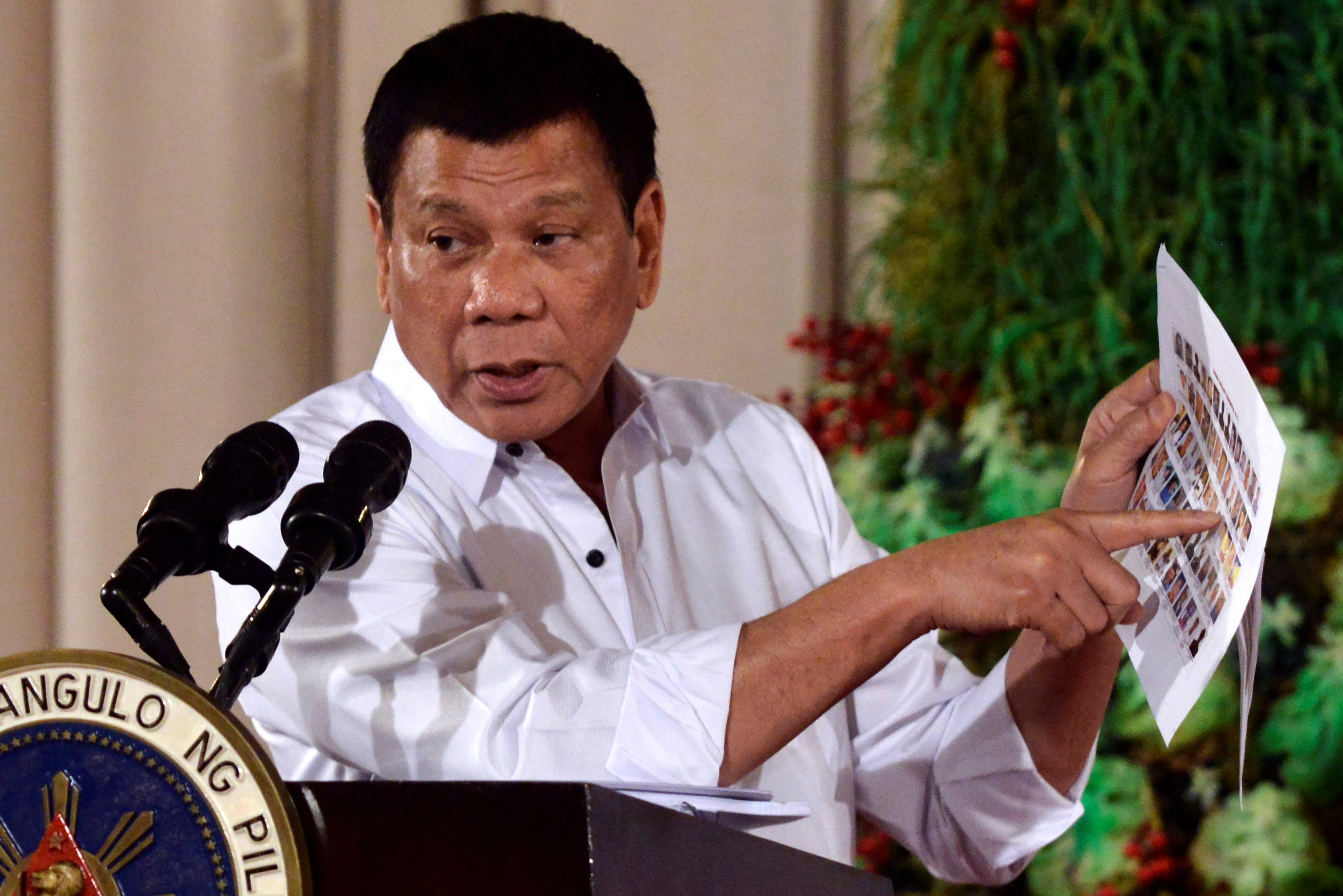 Philippine President Rodrigo Duterte points to a piece of paper containing a list of personalities he alleges are involved with the drug trade, as he delivers a speech during an awarding ceremony for outstanding Filipinos and organizations overseas, at th