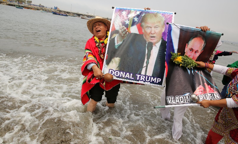 Peruvian shamans holding a poster of U.S. President-elect Donald Trump and Russian President Vladimir Putin perform a ritual of predictions for the new year at Pescadores beach in Chorrillos, Lima, Peru, December 29, 2016. REUTERS/Mariana Bazo