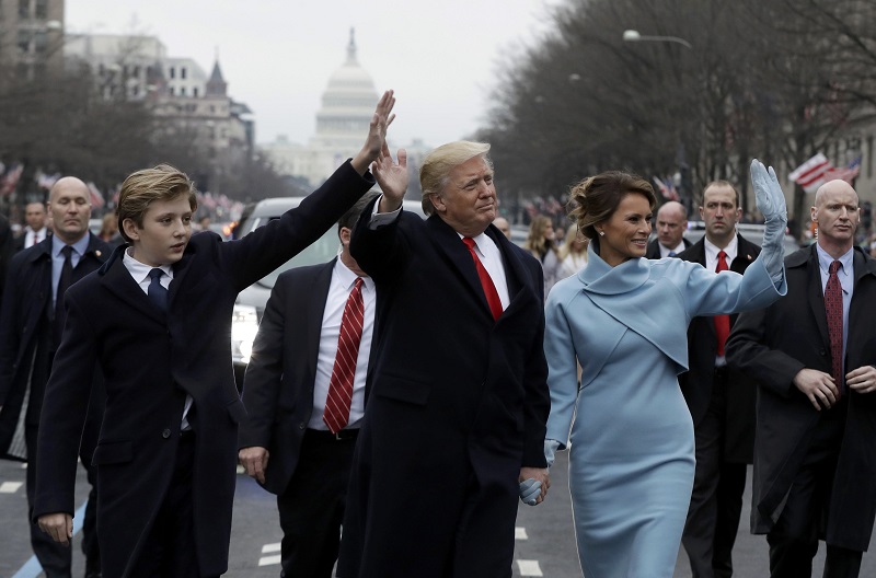 特朗普（中）与妻子梅拉尼娅（右）和幼子巴伦，在总统就职巡游上走了一小段路，并向民众挥手。-路透社-